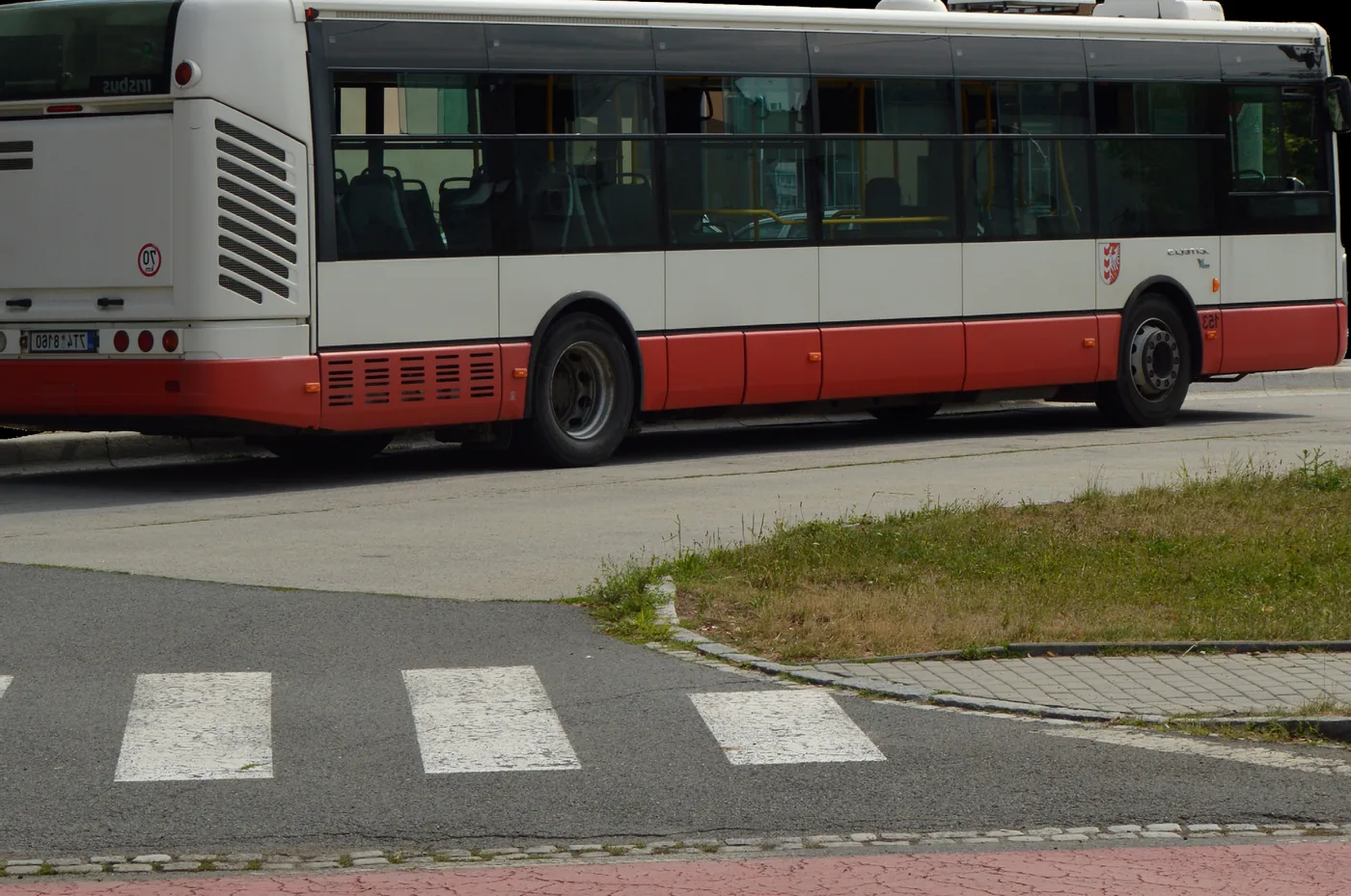 Autobus městské hromadné dopravy projíždějící kolem přechodu pro chodce.